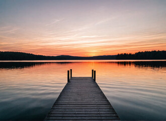 Fototapeta premium Sunset over a serene lake with a dock