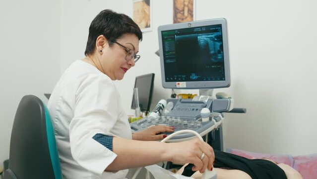 A female doctor conducts a detailed diagnosis of the patient's abdominal cavity. Ultrasound diagnosis of internal organs in the medical office. High quality 4k footage