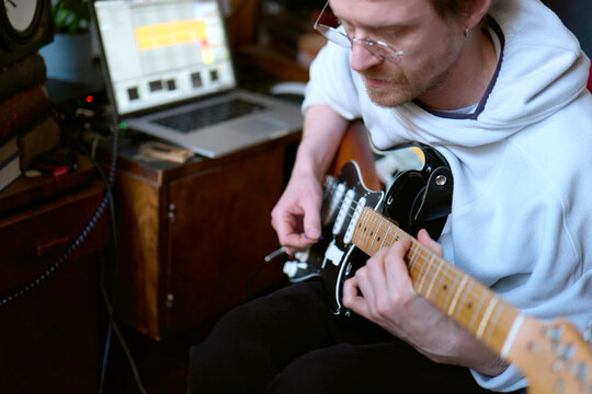 Musician recording guitar track in home studio