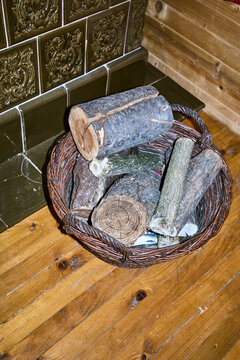A pile of firewood lies in a basket near the stove