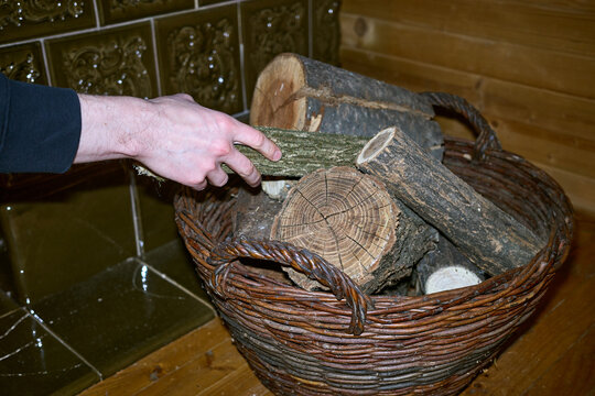 A young man takes a log to fire the stove