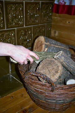 A young man takes a log to fire the stove