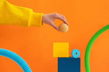 Hand in yellow sleeve adds a sphere to abstract geometric composition