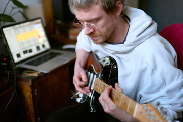 Musician recording guitar track in home studio