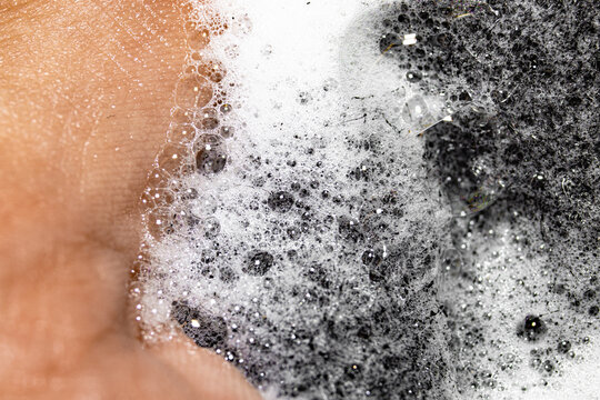 Hand Squeezes Out Soap Foam Of Black Dish Sponge