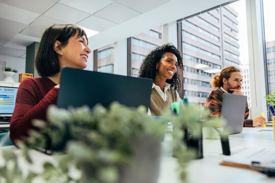 Diverse team smiling and working in modern office - Powered by Adobe