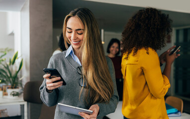 Smiling businesswoman using smartphone in modern office