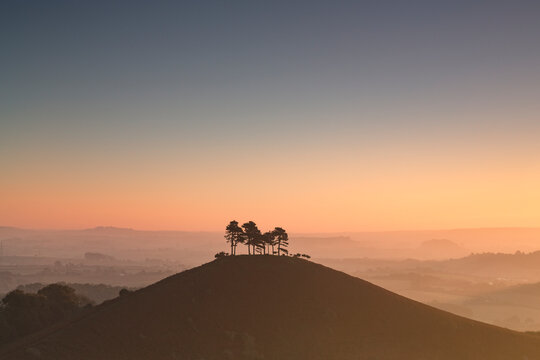 A lone conical silhouetted hill at daybreak.