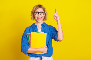 Photo of nice young girl hold book point finger wear blue shirt isolated on yellow color background