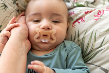  baby resting on a bed, being gently held by mother