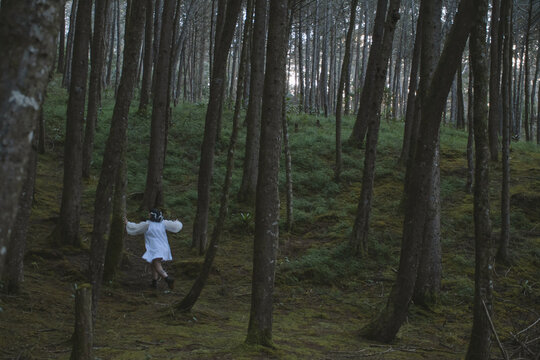 Woman with white dress running in the middle of the woods 
