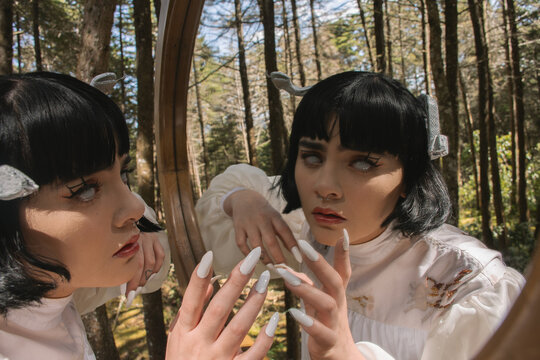 Forest portrait: Woman in a costume looking at herself in a mirror,