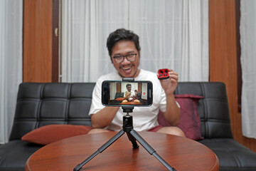 Close up of blogger filming video with smartphone on tripod for online vlog. Content creator using mobile phone and videography equipment to record for content on social media.