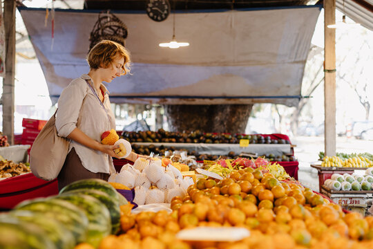 Young woman choosing fruits in authentic market