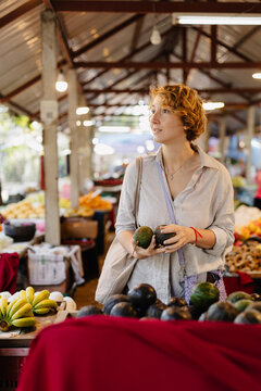 Woman with reusable bag buying avocados in market