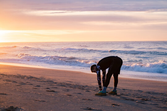Straching before morning run on the beach.