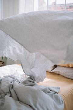 White linen sheet flying over a cozy bed