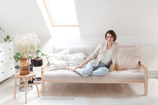 Young woman relaxing on her white sofa in her white room. 