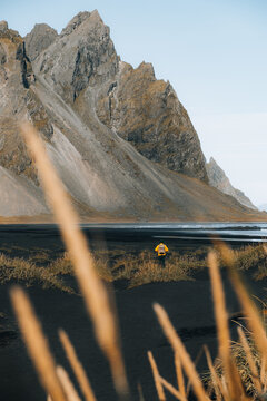 unrecognizable man exploring black sand beach, mountains, ocean. 