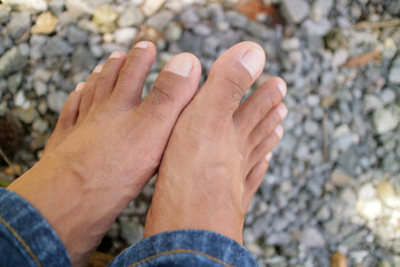 a pair of men legs, dark brown in color. around thirty years old. gravel background