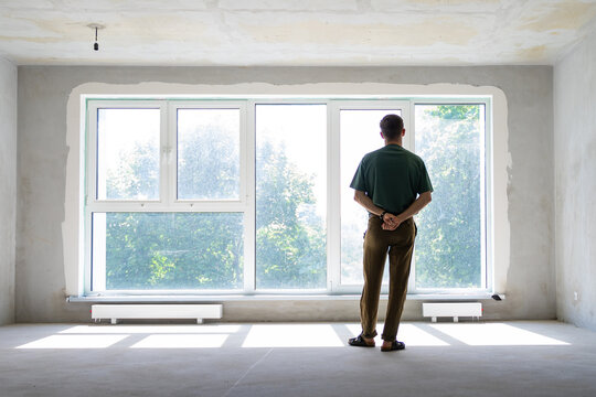 unrecognizable millennial man in front of window in a new empty home