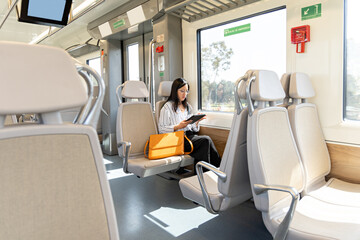 A professional woman utilizes a tablet for work in an electric train
