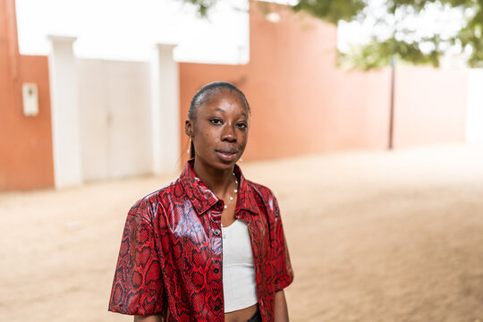 Senegalese Woman in Red Patterned Shirt Standing on a Sandy Street