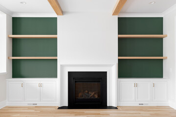 A fireplace detail with built-in white oak shelving, white oak flooring and beams, green accents, and white marble surrounding the fireplace.
