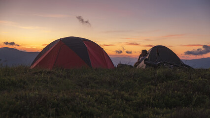 Man with bike in camping tent call by his phone.
