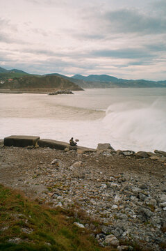 A sound recordist captures the noises of waves breaking on the rocks