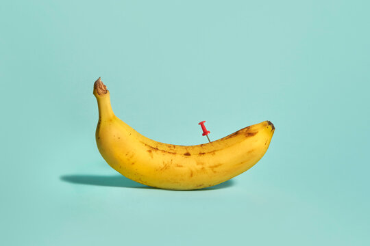 Connection. Yellow banana with red pushpin on cyan colored background