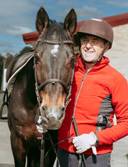 Smiling senior man with horse before riding