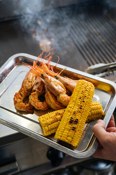 Person Holding Tray of Food on Grill