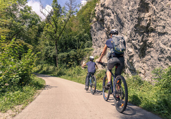 Mother and young son riding bikes along a scenic rural landscape. Outdoors family activity concept.