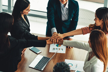 Businesswomen joining hands in group meeting at modern office room showing teamwork, support and...