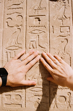 Hands of a married couple over ancient Egyptian hieroglyphs