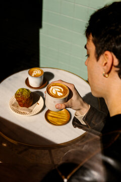 A youthful man is relishing a cappuccino adorned with latte art