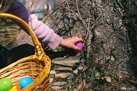 Child's Hand Reaches for Easter Egg Hidden Outside