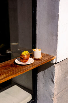 Croissant and a cup of coffee with latte art placed on a wooden bar