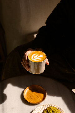 A hand holding a cup of specialty white flat adorned with latte art
