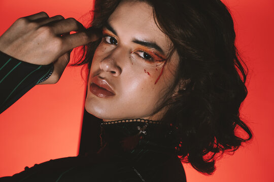 Dramatic portrait of a young queer man with a vampire make up 