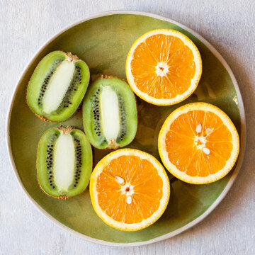 Kiwi fruit and sliced oranges on white background