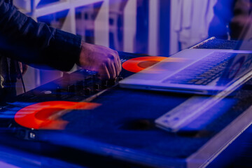 DJ mixing music at a club with vinyl and laptop