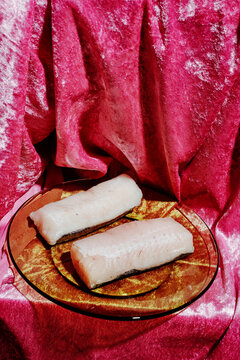 raw hake loins on an orange glass plate
