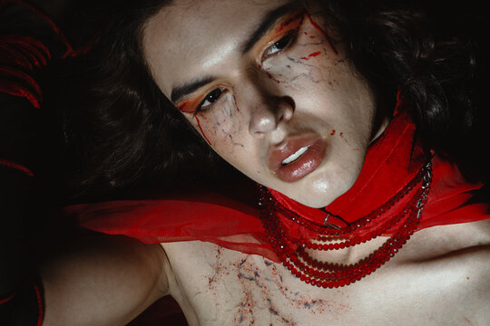Dramatic portrait of a young queer man with a vampire make up 