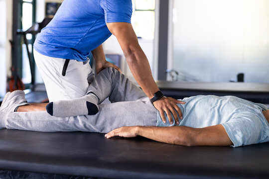 Biracial male therapist and patient doing rehab exercises at rehabilitation center