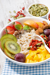 oatmeal porridge with fresh fruits and superfoods for breakfast, closeup