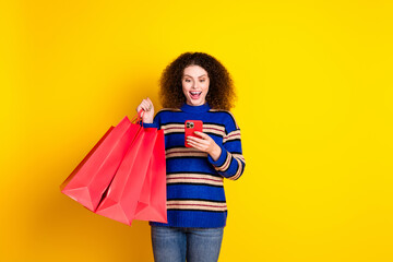 Portrait of impressed woman wear knit sweater holding shopping bags staring at smartphone in hand...