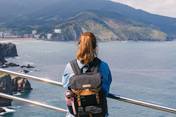 Woman tourist with a backpack looking on the scenic landscape at San Sebastian, Spain