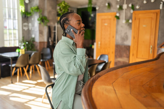 black woman using mobile phone in a cafe - Powered by Adobe